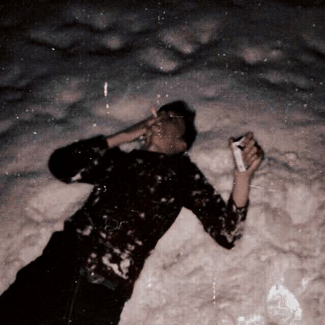 a man laying in the snow with his mouth open and holding a cell phone to his ear