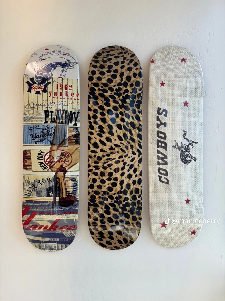 three skateboards are lined up on the wall and one is decorated with an animal print