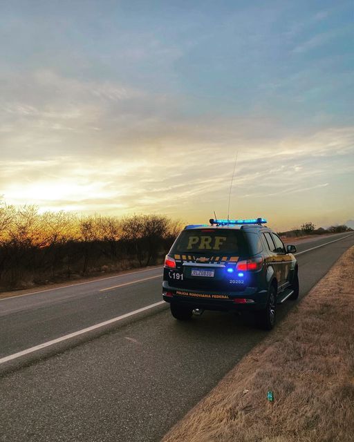 a police car is parked on the side of the road with its lights on at sunset