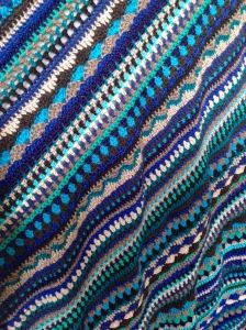 a crocheted blanket with blue and gray stripes