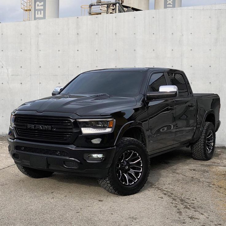 a black truck parked in front of a white wall