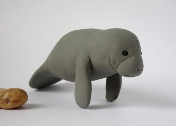 a small stuffed animal next to a cookie on a white surface with a light gray background