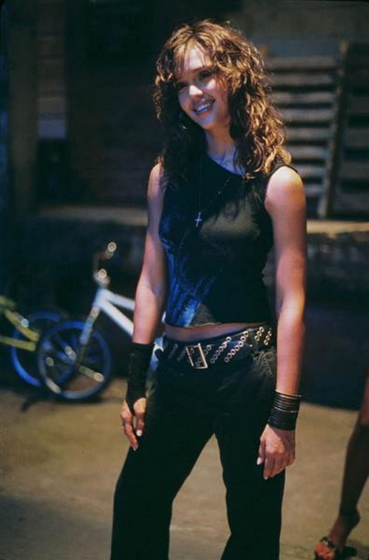 a woman standing in front of a bike wearing black pants and a cropped top