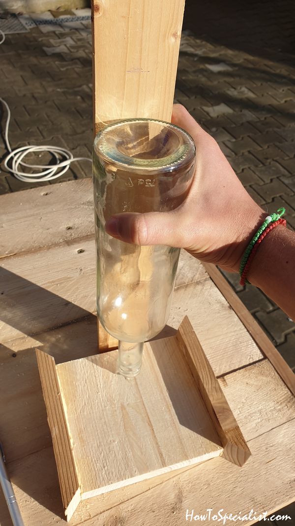 a person holding a glass with water in it on a wooden stand outside near a tree