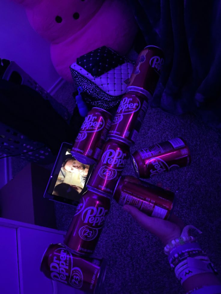 a person is holding up some purple cans