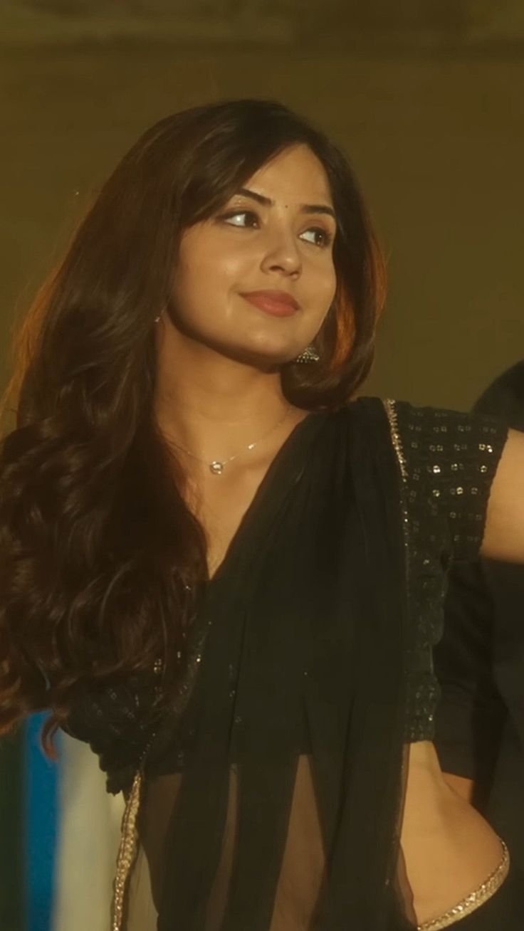 a woman with long dark hair wearing a black dress and posing for the camera in front of an audience