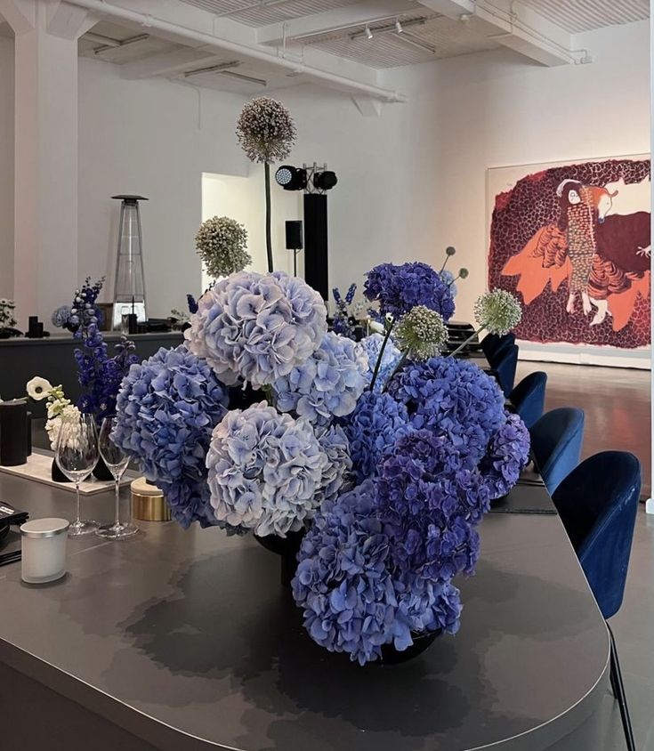 a vase filled with blue flowers sitting on top of a table next to a mirror