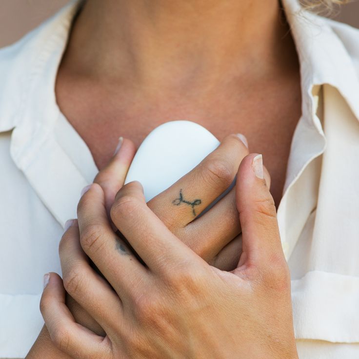 a woman with a cross tattoo on her left hand holding a white heart shaped object