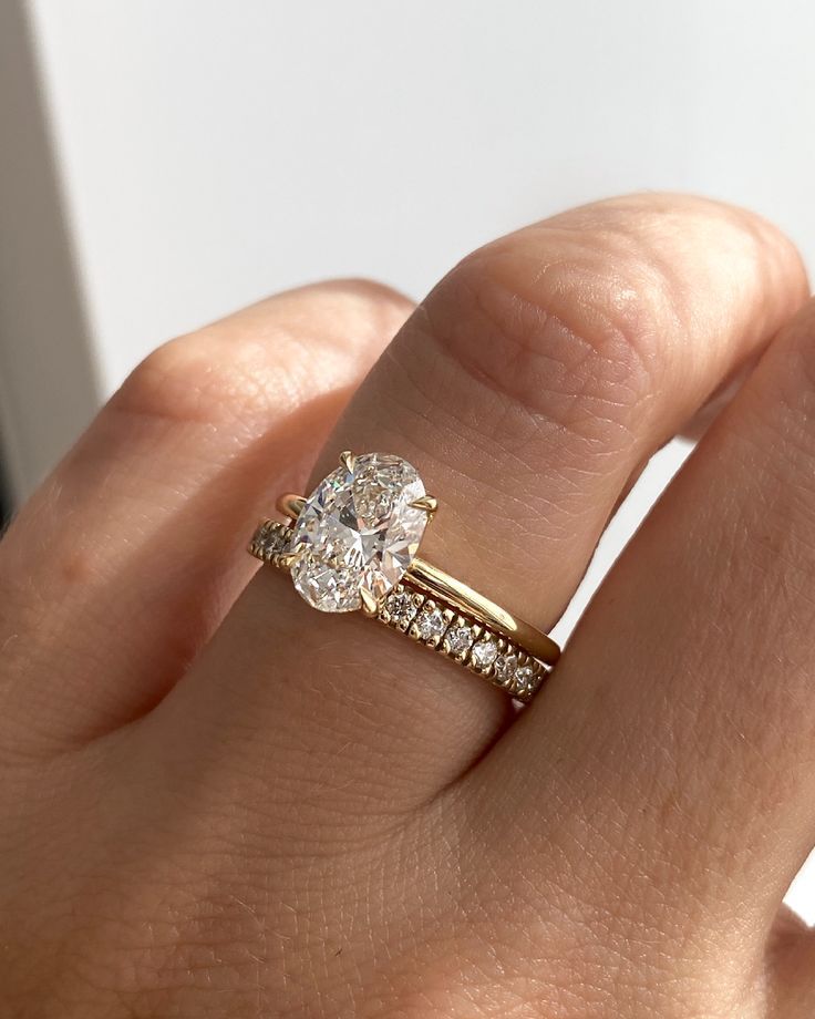 a woman's hand with a diamond ring on top of her finger and an engagement band