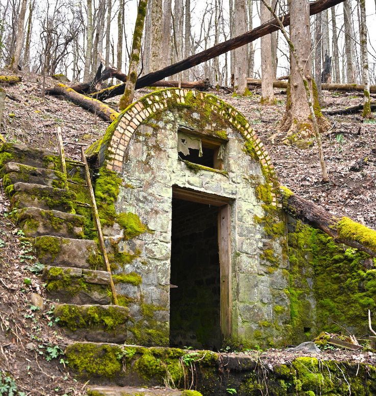 an old stone building with moss growing on the side and steps leading up to it