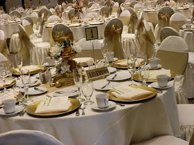 the tables are set with white linens and gold place settings