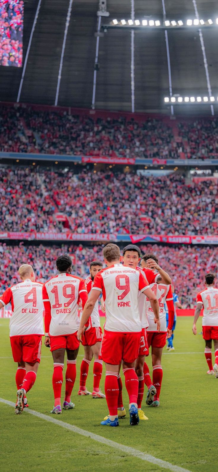 a group of men standing on top of a soccer field in front of a crowd