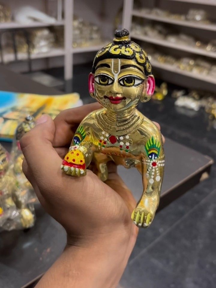 a person holding a small gold figurine in their hand with other items on the table behind them