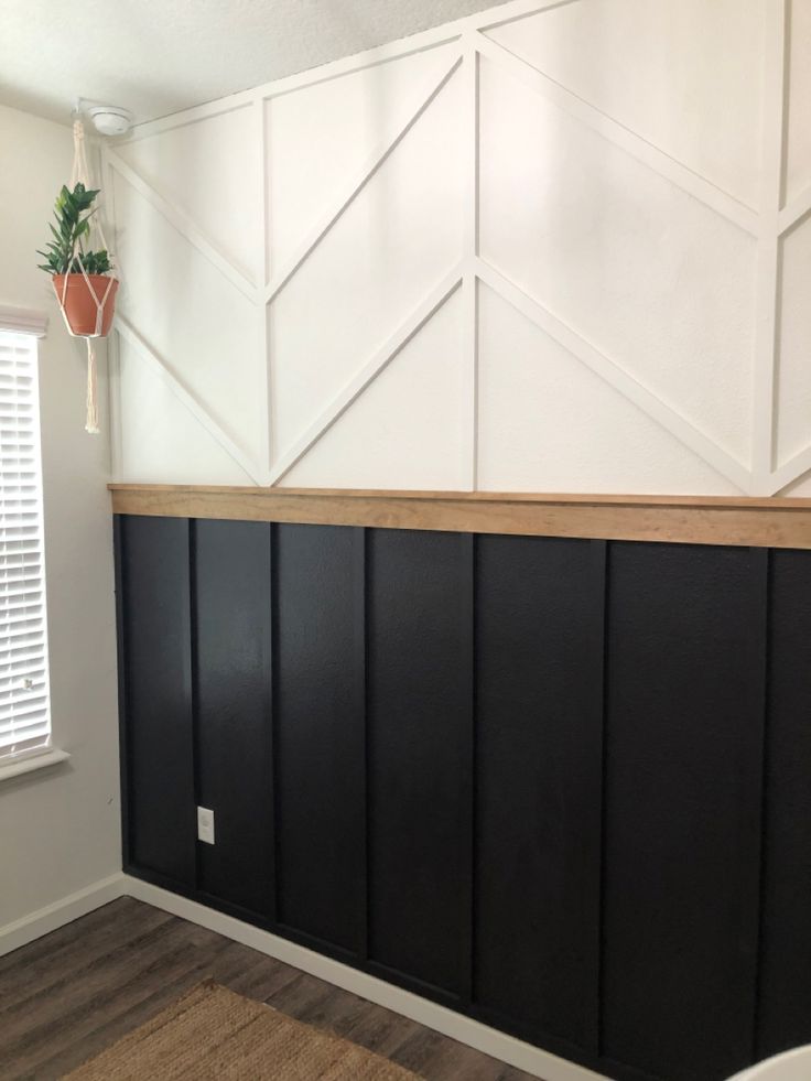 an empty room with black paneling and white walls in the background, there is a potted plant hanging on the wall