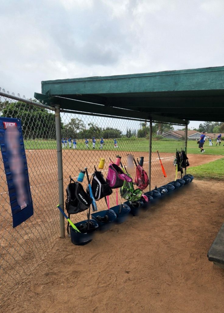 a baseball field with several bags and equipment hanging on the side of the fence,