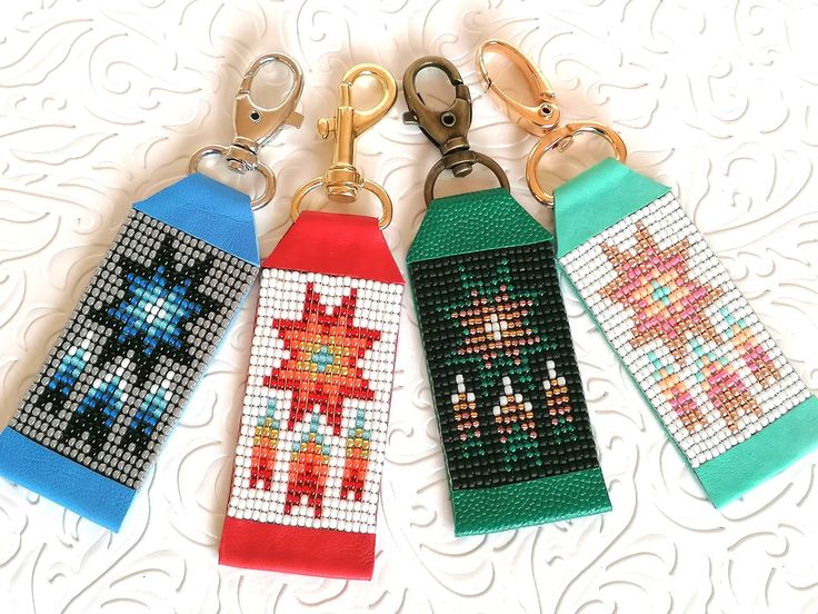 four cross stitch key fobs are lined up on a table