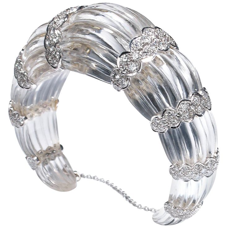 A modern, fluted rock crystal bangle bracelet, carved from one single piece of rock crystal, with eight scalloped 18ct white gold sections, each set with round brilliant-cut diamonds, weighing an estimated total of 7.00 carats. With a white gold safety chain. Approximate wrist measurement: 171mm Diamond Dress Ring, Diamond Tops, Diamond Cuff Bracelet, Three Stone Diamond Ring, Diamond Cluster Earrings, Platinum Earrings, Yellow Diamond Rings, Beautiful Bracelets, Vintage Sapphire