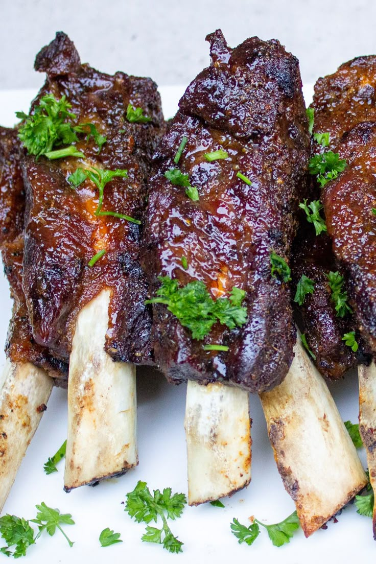 several pieces of meat with parsley on the top and bottom, sitting on a white plate