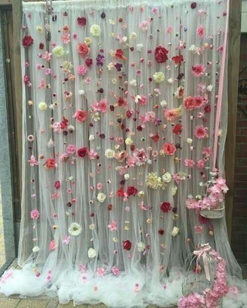 a white curtain with pink and red flowers hanging from it