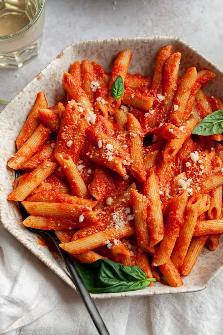 a bowl filled with pasta covered in sauce and parmesan cheese on top of a table