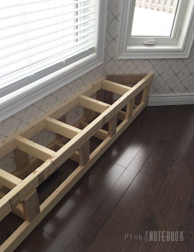 a wooden bench sitting in front of a window on top of a hard wood floor