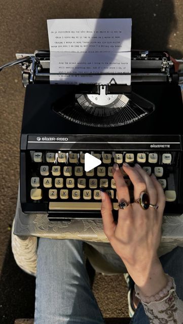 a person typing on an old fashioned typewriter with a sheet of paper attached to it