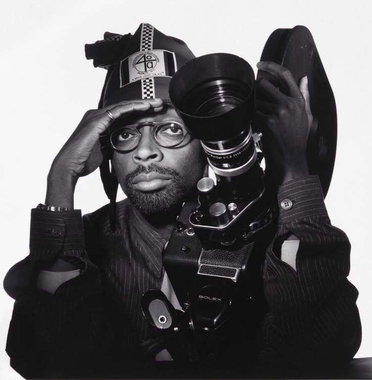 a black and white photo of a man holding a camera in front of his face