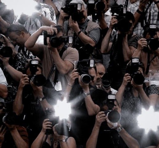 a large group of people holding up cameras and taking pictures with their cell phones in front of them