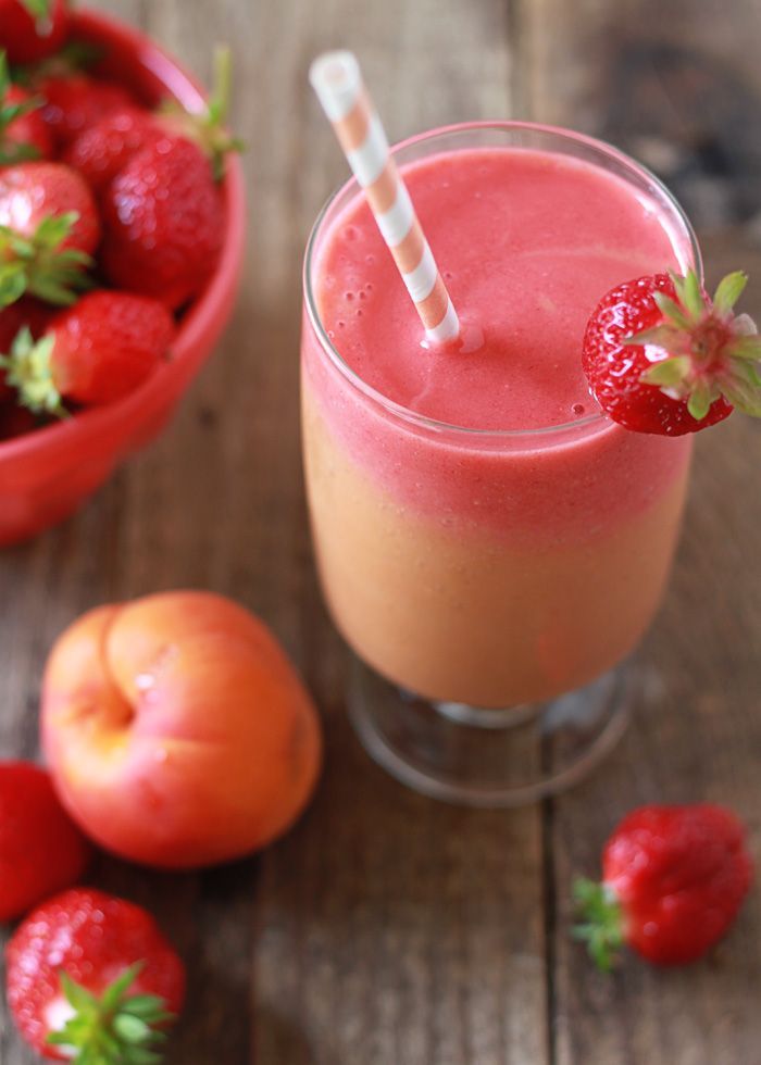 a smoothie with strawberries and oranges on the table