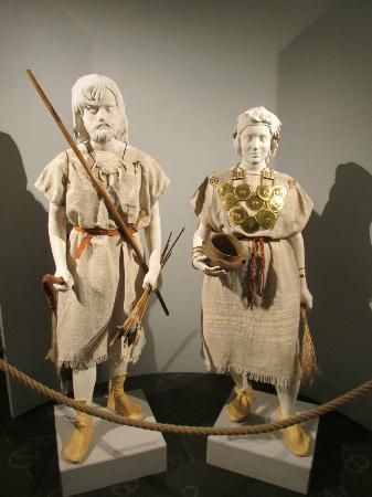 two statues of men with spears and masks on display