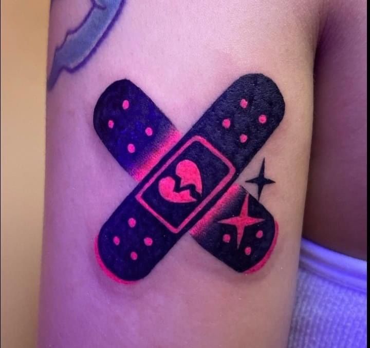 a tattoo on the arm of a person with a pink and black cross in it