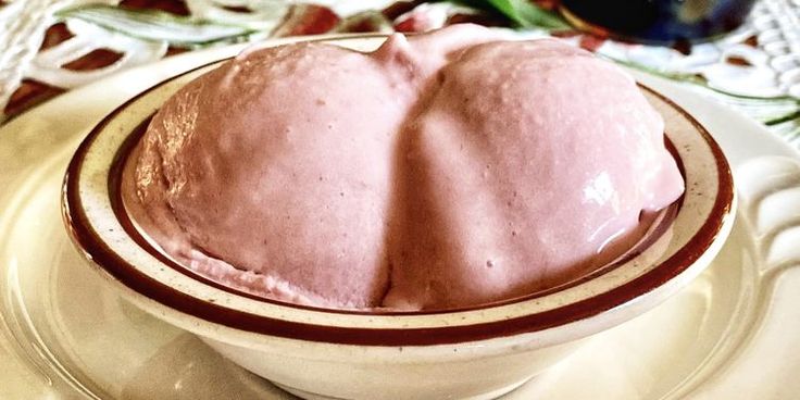 a bowl filled with pink ice cream on top of a white plate