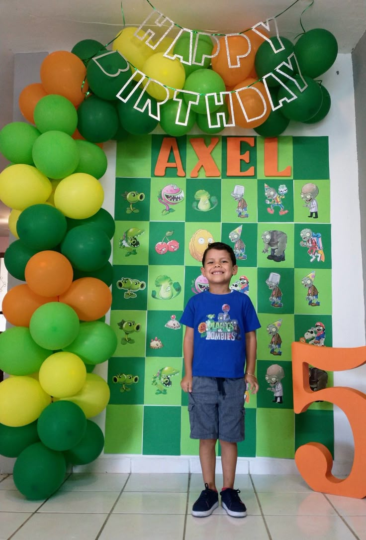 a young boy standing in front of a birthday backdrop