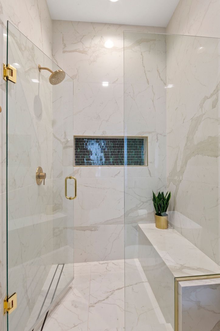 a walk in shower sitting next to a white counter top with a potted plant