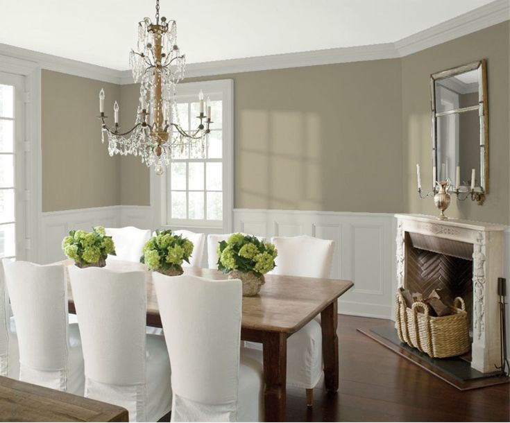 a dining room table with white chairs and green flowers in vases on the top