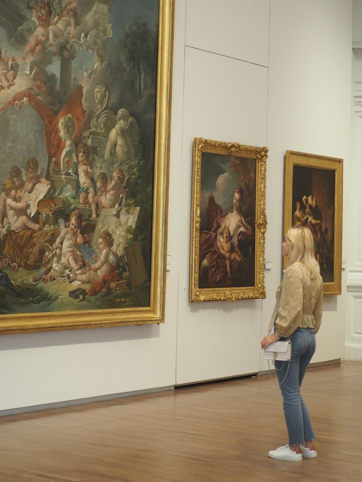 a woman is looking at paintings in an art gallery