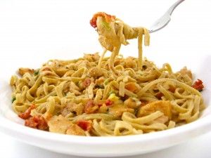 a plate of pasta with chicken and tomato sauce being held by a fork over it