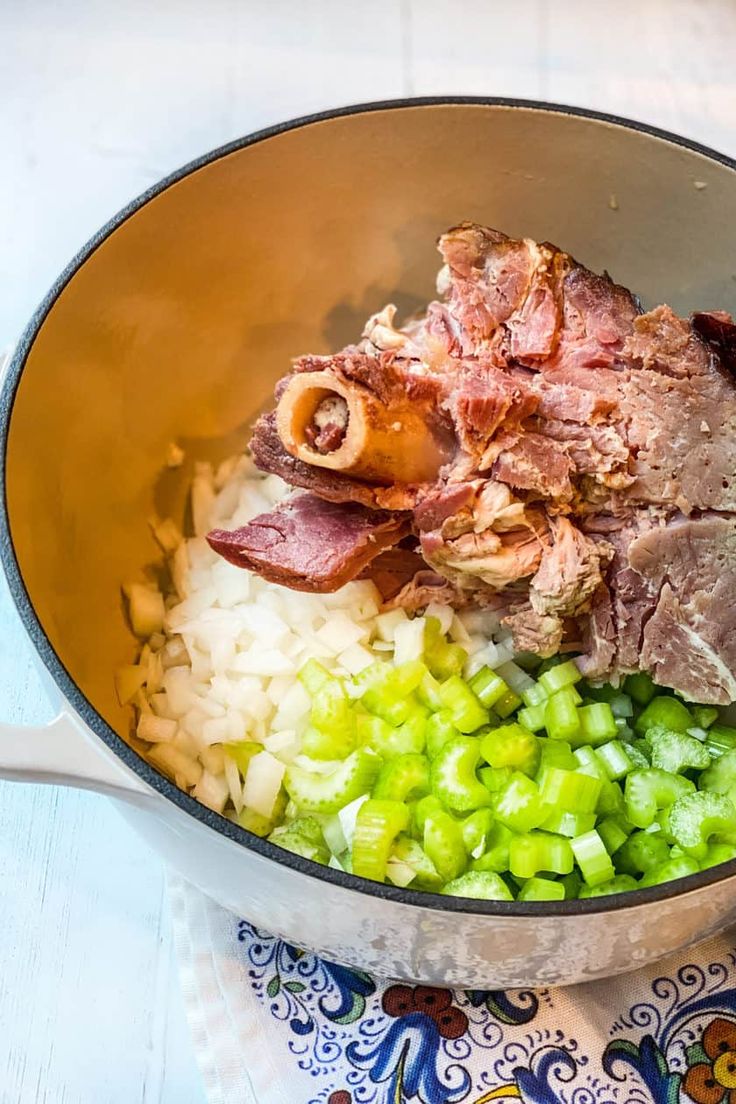 meat, onions and celery in a pot on a table