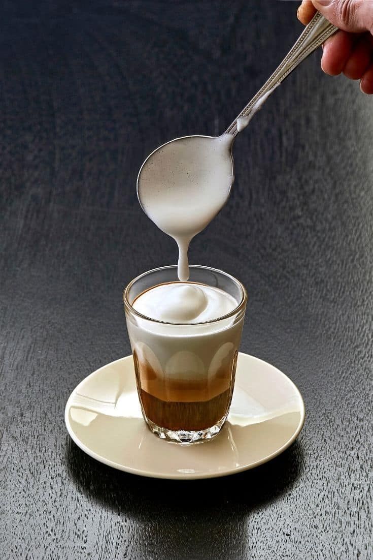 a spoon pouring liquid into a cup on top of a saucer