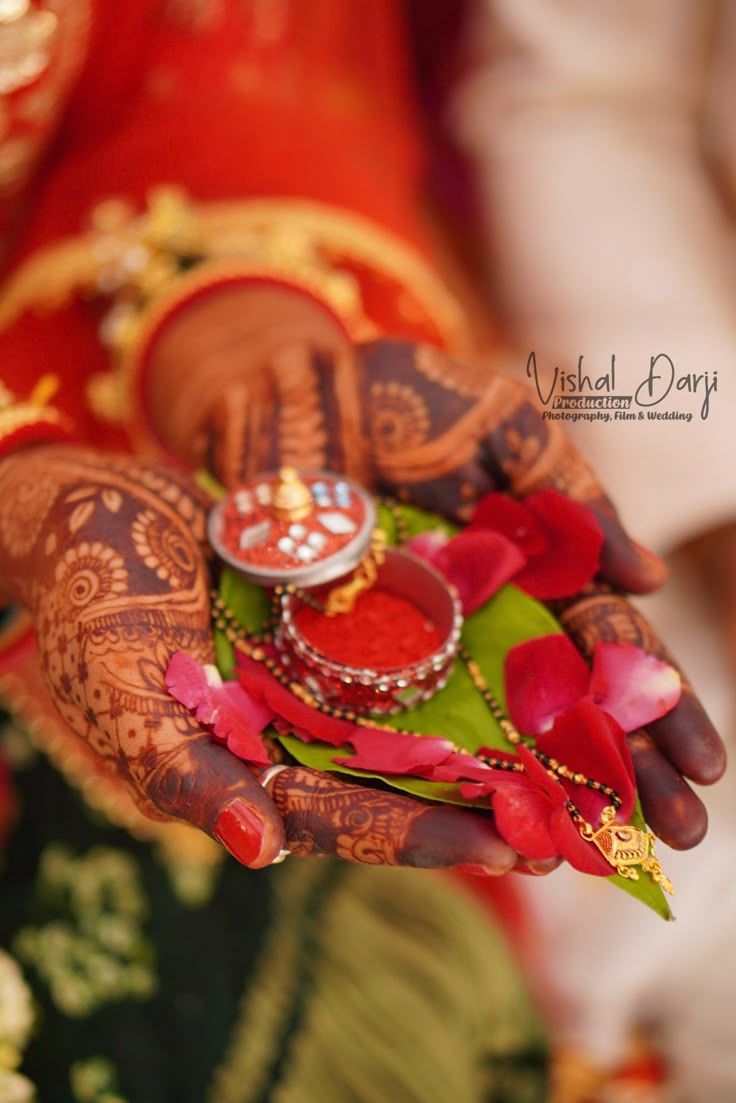 the hands of a woman with henna and jewelry on their palms are holding flowers