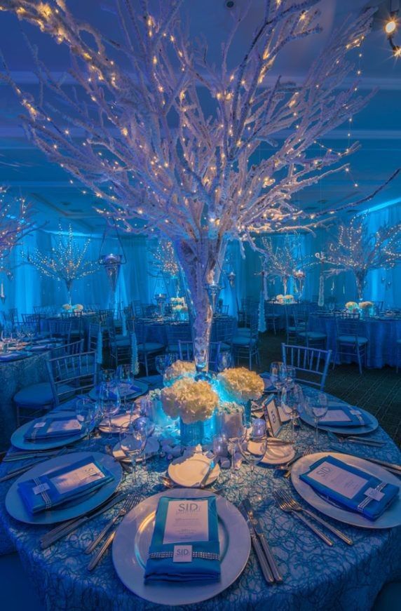 the table is set with blue linens, silverware and white place settings for an elegant dinner