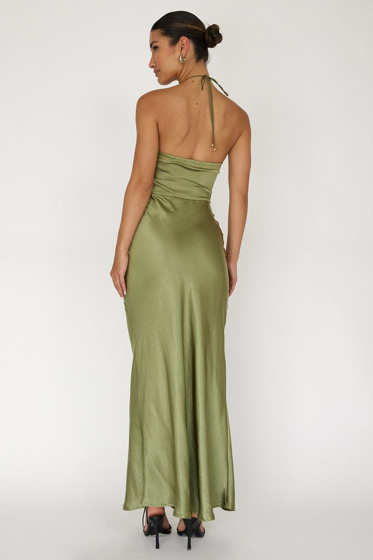 a woman in a green dress with her back turned to the camera and wearing high heels