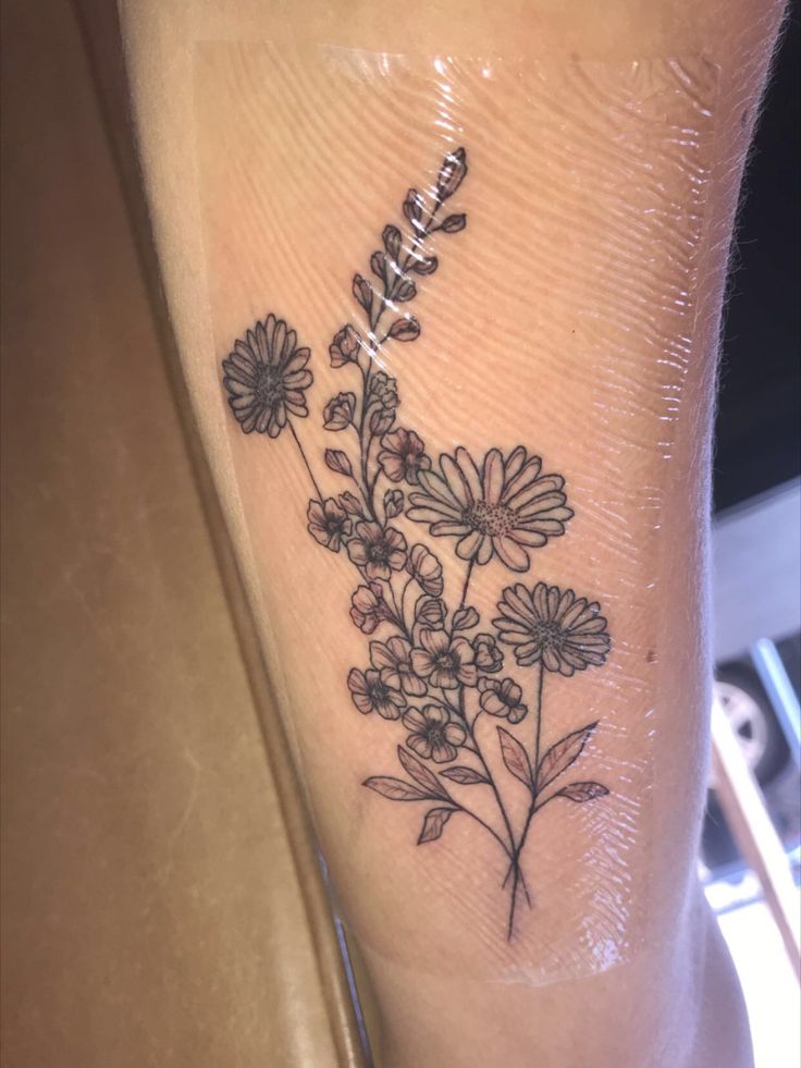 a small flower tattoo on the ankle that is black and white, with flowers growing out of it