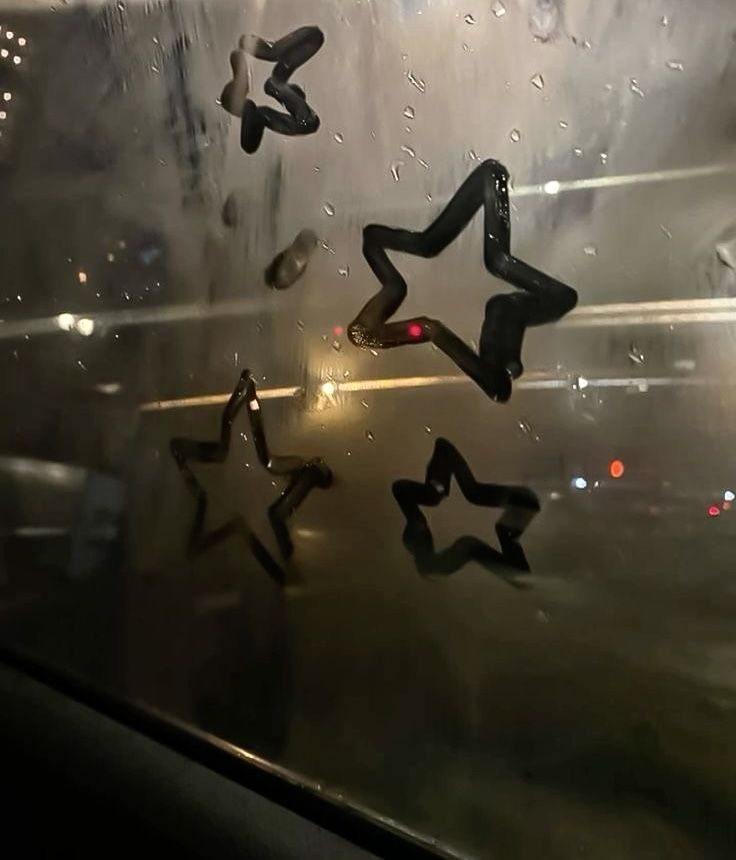 the rain is falling on the window and stars are reflected in the wet glass surface