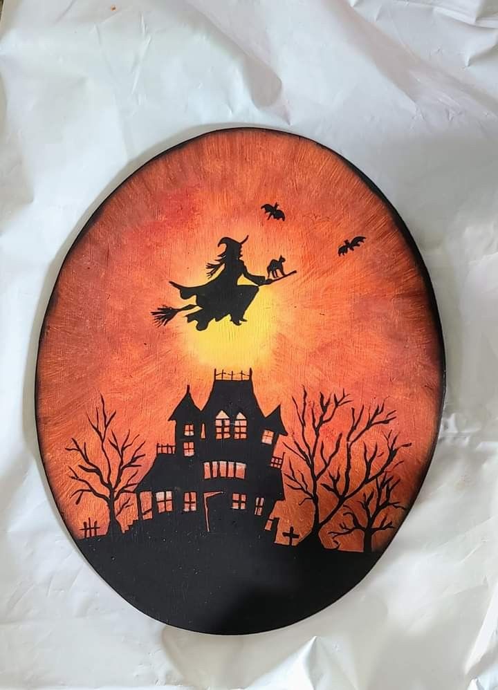 a halloween scene painted on a plate with bats and witches flying in the sky over a house