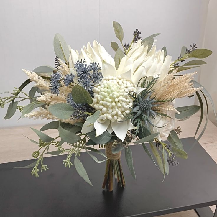 a vase filled with white flowers and greenery