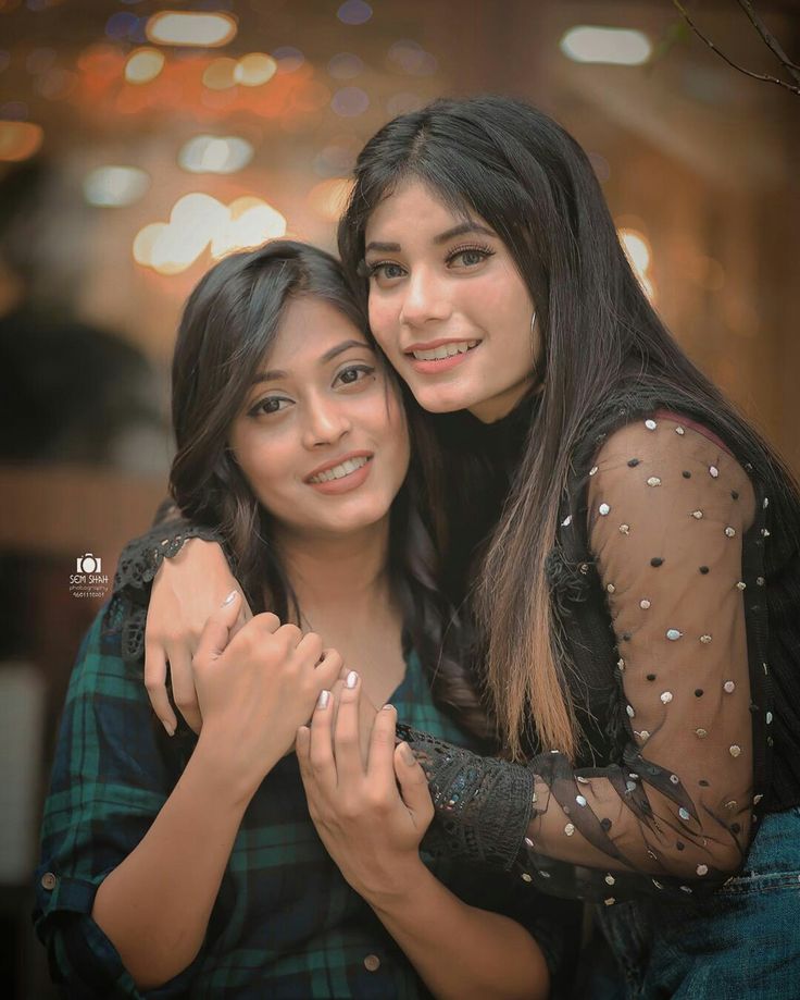 two young women hugging each other in front of lights