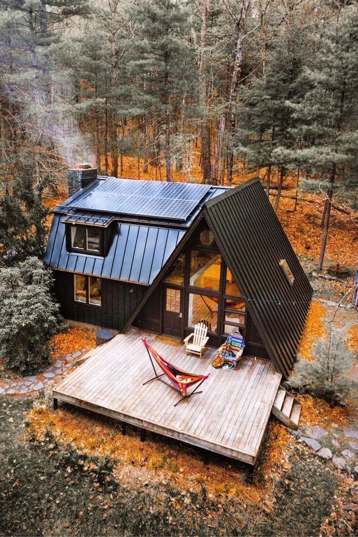 a small cabin in the woods with a hammock hanging from it's roof