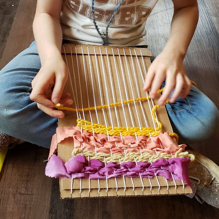 a person sitting on the floor working with some string art pieces in front of her