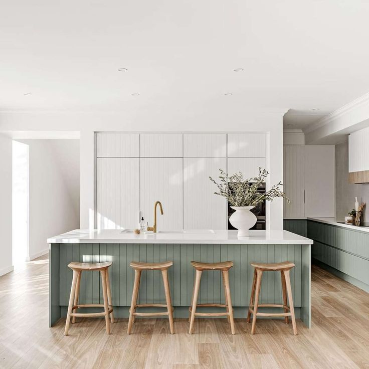 an open kitchen with three stools in front of the island and two vases on the counter